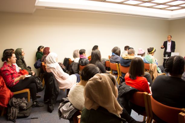 People sitting listening to a standing speaker